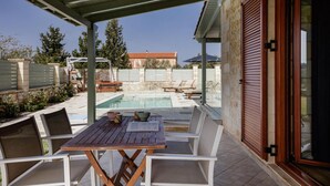 Un'area esterna coperta con piscina, posti a sedere e un muro in pietra.