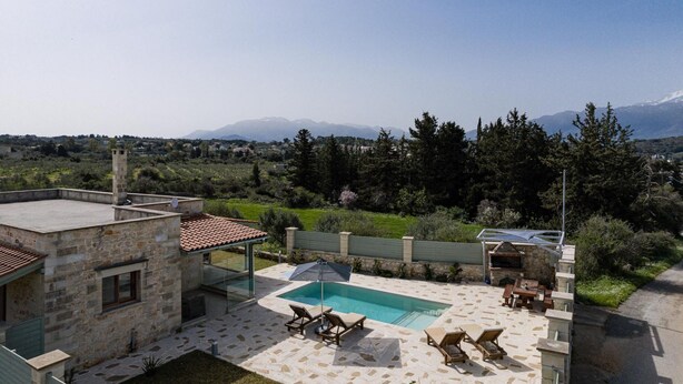 Una casa in pietra con piscina, area relax all'aperto e vista sulle montagne.