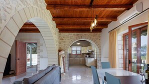 Un'ampia zona giorno con soffitto in legno, pareti in pietra, un divano e un tavolo da pranzo con sedie.