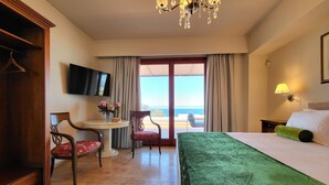 Een hotelkamer met een bed, een bureau, een stoel, een televisie en een balkon met uitzicht.