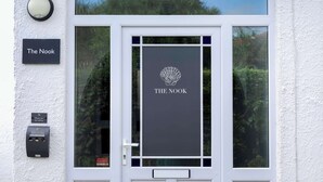A white-framed door with a sign reading 'The Nook' and a logo above it.