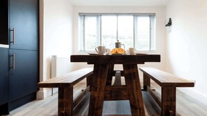 A wooden bench table with a window view, a radiator, and a dark cabinet. - The Nook - Room 4 - Deluxe King Room (St Ives)