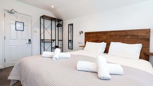 Hotelkamer met een groot bed, een houten hoofdbord, een wandlamp en een deur met een veiligheidssymbool.