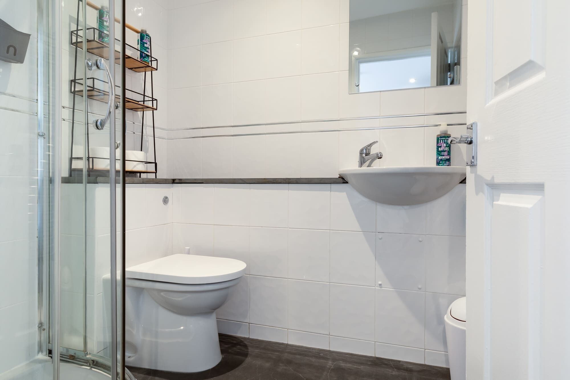 A modern bathroom with a glass shower enclosure, a white toilet, and a sink.