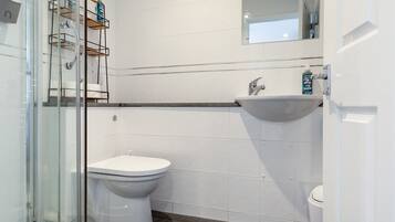 A modern bathroom with a glass shower enclosure, a white toilet, and a sink.