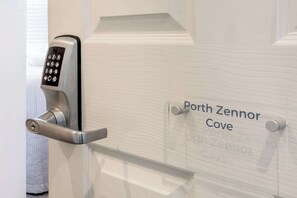 A door with a keypad lock and a sign reading 'Porth Zennor Cove.'