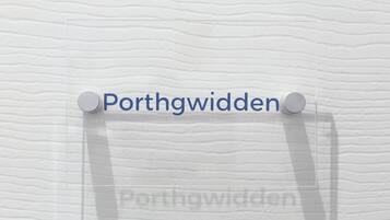 A sign with the text 'Porthgwydden' pinned to a textured wall.