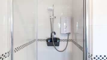 Ducha con cabezal de ducha manual, panel de control en la pared y un accesorio de ducha de mano.