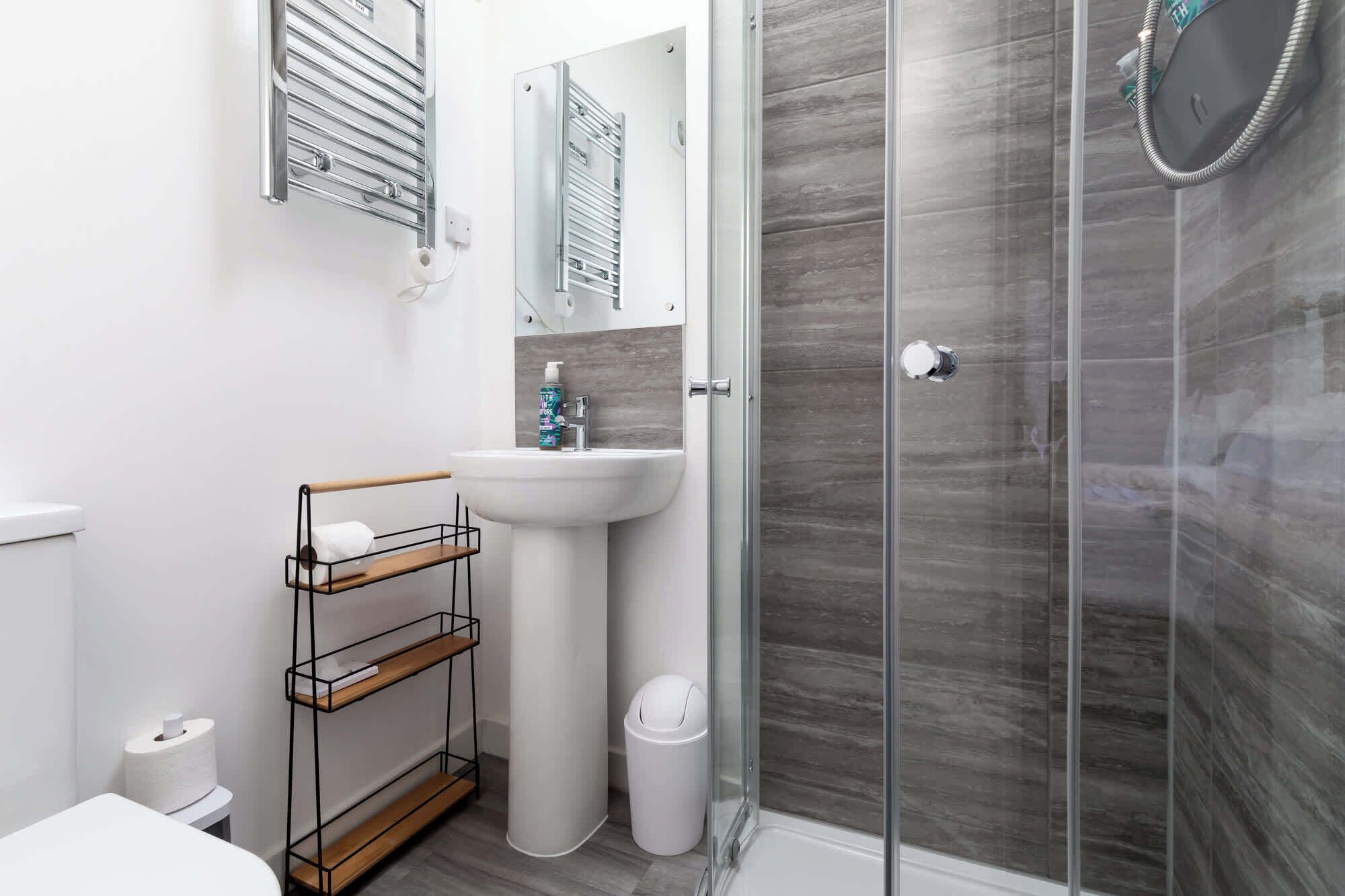 A modern bathroom with a glass shower enclosure, a white sink, and a toilet.