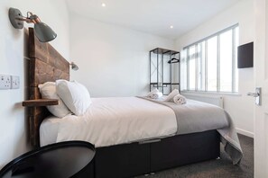 Quarto com cama, abajures, um cabideiro e uma janela.