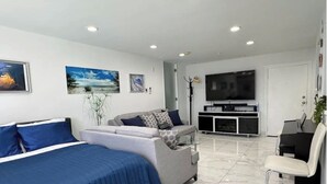 Ett modernt hotellrum med en stor säng, en soffa, en TV och en matplats.