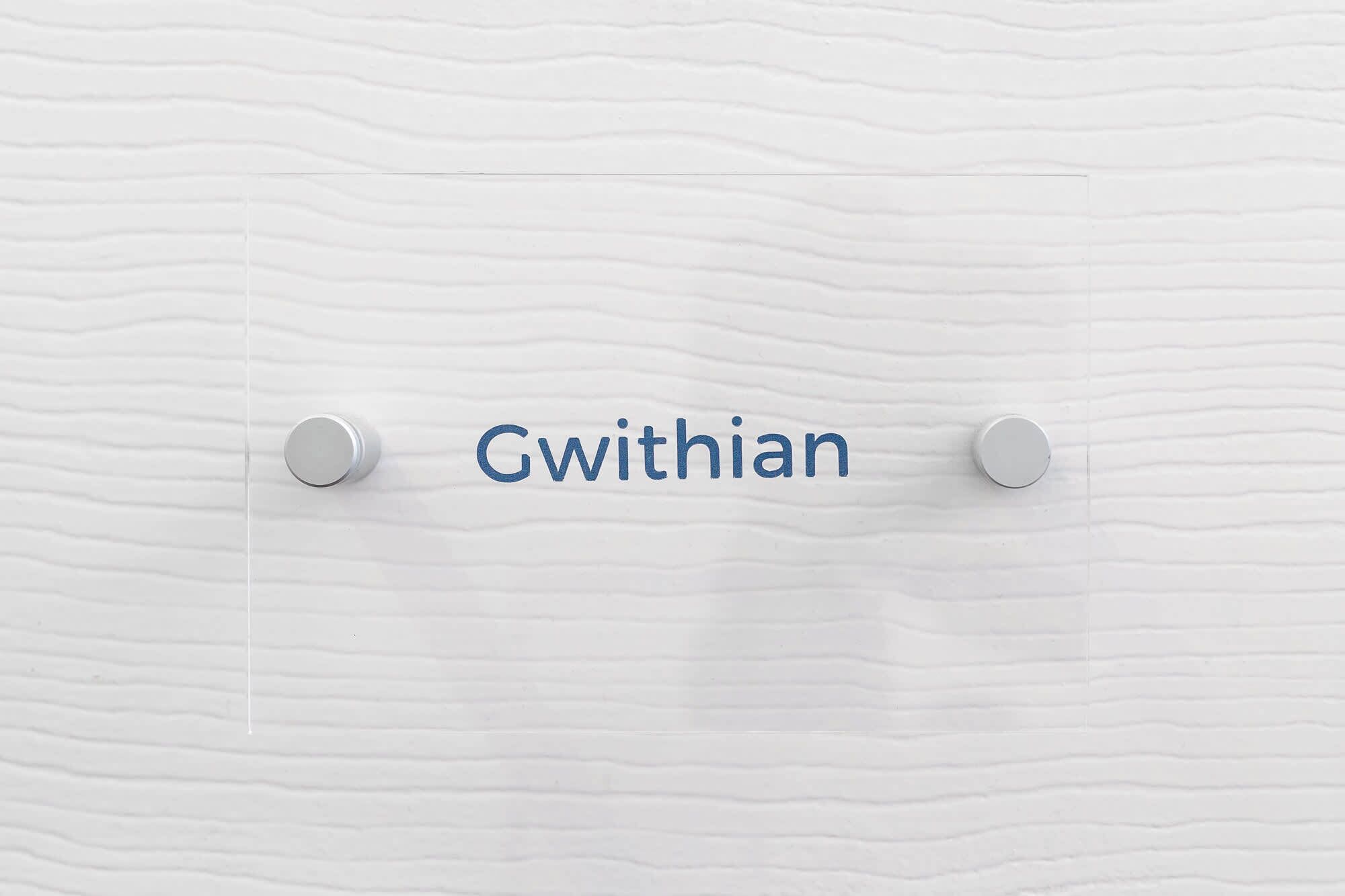 A textured wall with the word 'Gwithian' centered between two metallic round knobs.