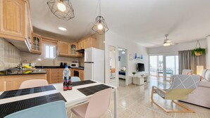 A modern kitchen with wooden cabinets, a dining table with chairs, and a living area with a sofa and a chair. - Casa Ramé - Beachfront with AACC By LVH (Puerto del Carmen)