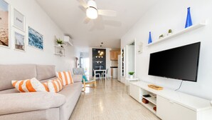 A modern living room with a sofa, TV, and a dining area in the background. - Casa Ramé - Beachfront with AACC By LVH (Puerto del Carmen)