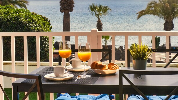A balcony with a table set for breakfast, overlooking the sea. - Casa Ramé - Beachfront with AACC By LVH (Puerto del Carmen)