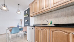 A modern kitchen with wooden cabinets, a dishwasher, a sink with a faucet, and pendant lights. - Casa Ramé - Beachfront with AACC By LVH (Puerto del Carmen)