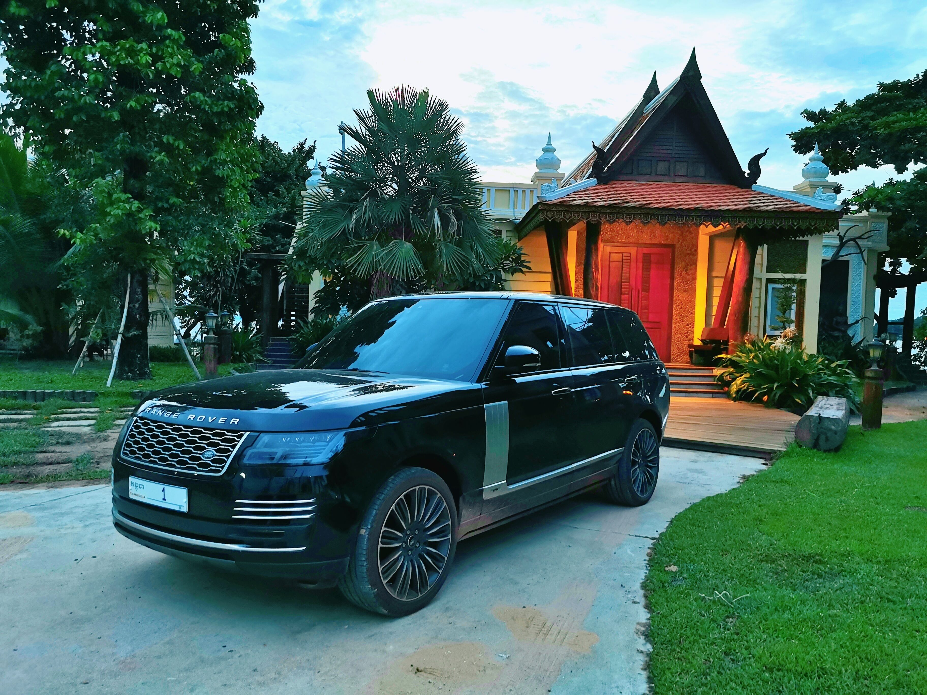 A black Range Rover SUV parked in front of a traditional building with a red door and a white roof.