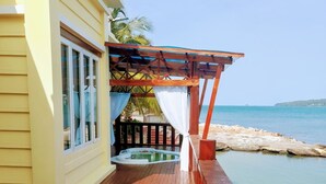 Une terrasse en bois avec un jacuzzi et vue sur la mer.