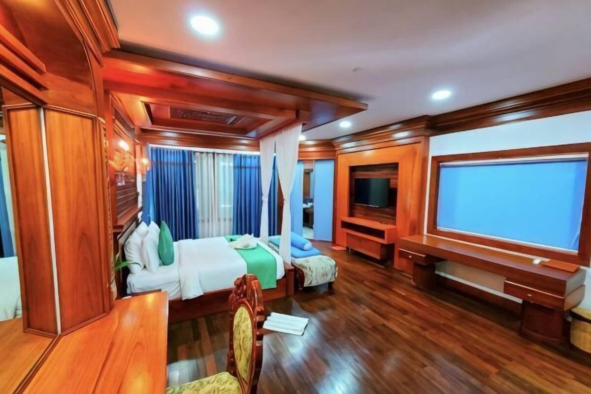 Een kamer met een bed, een bureau, een stoel, een televisie en een raam.
