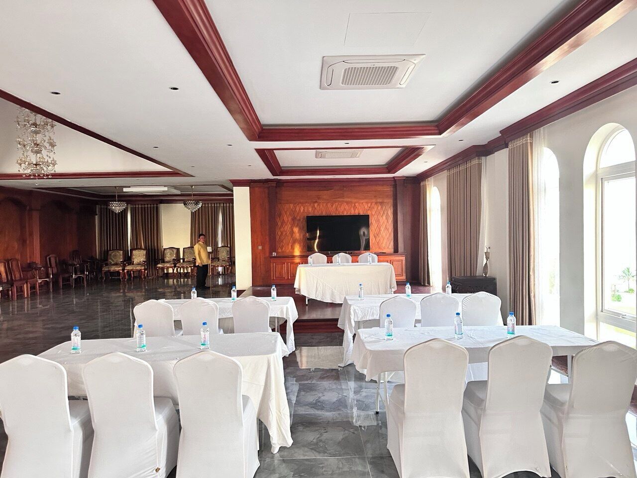 A conference room with round tables and chairs, a large screen, and a wooden panel wall.