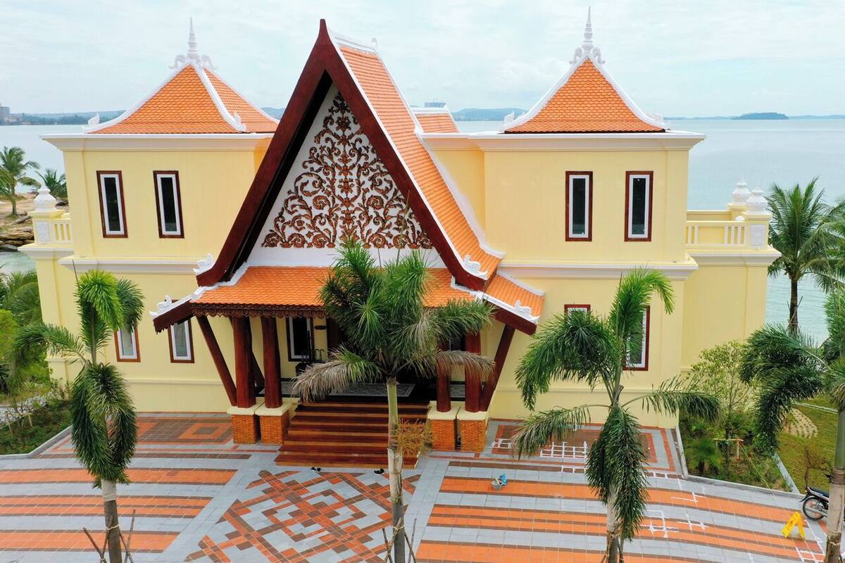 Een groot, geel gebouw met een traditionele architectuur, inclusief een centraal paviljoen met een decoratieve gevel en meerdere dakpunten.