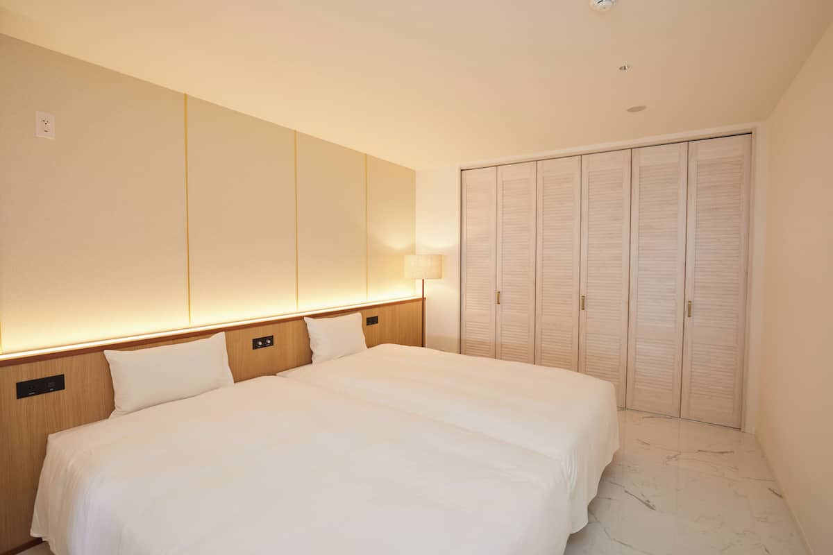 A hotel room with a large bed, a wardrobe with sliding doors, and a wall-mounted light fixture.