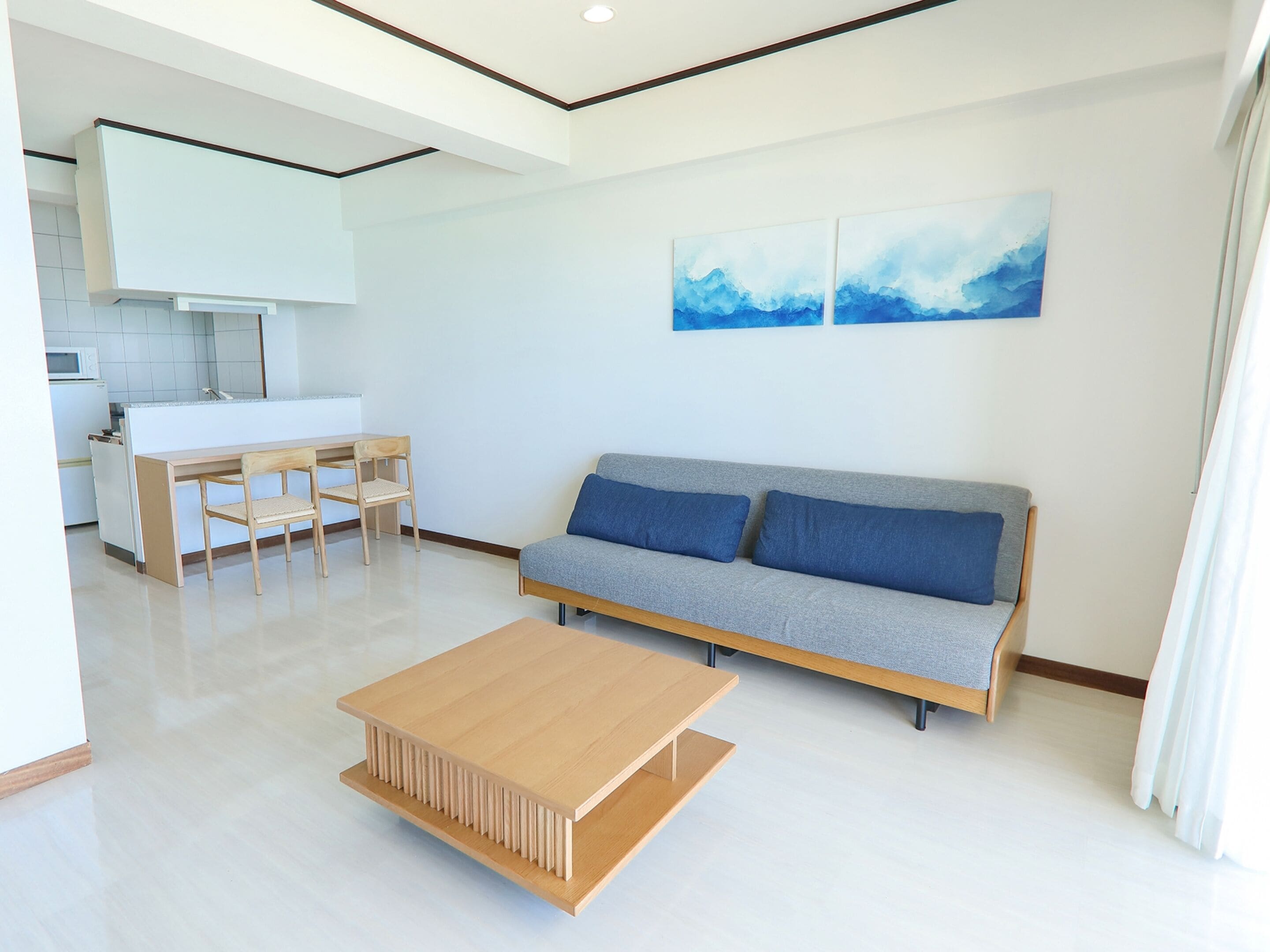 A modern living room with a sofa, a coffee table, and a dining area with a table and chairs.