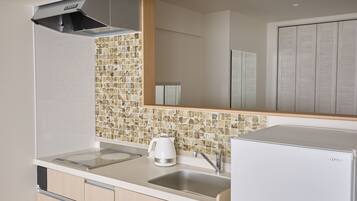A modern kitchen with a built-in stove, a coffee maker, and a refrigerator.