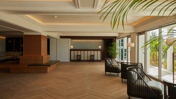 A spacious lobby with a herringbone wood floor, a reception desk, and seating areas with modern chairs.