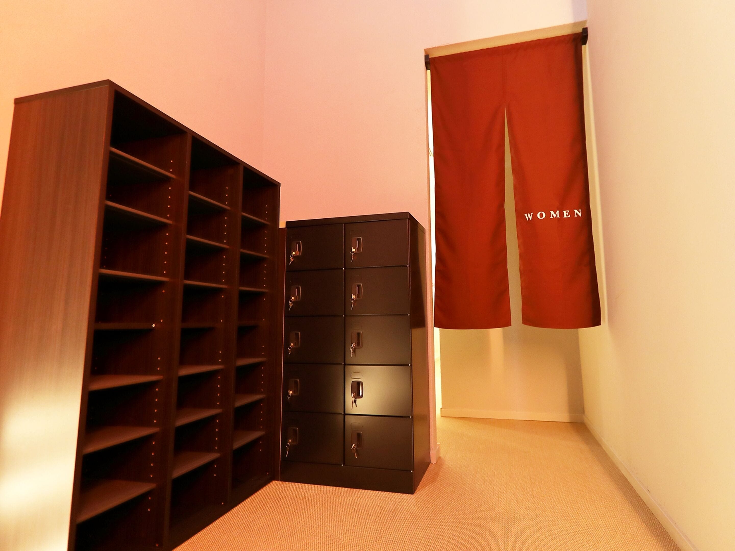 A corner of a room with a wooden shelving unit and a black filing cabinet.