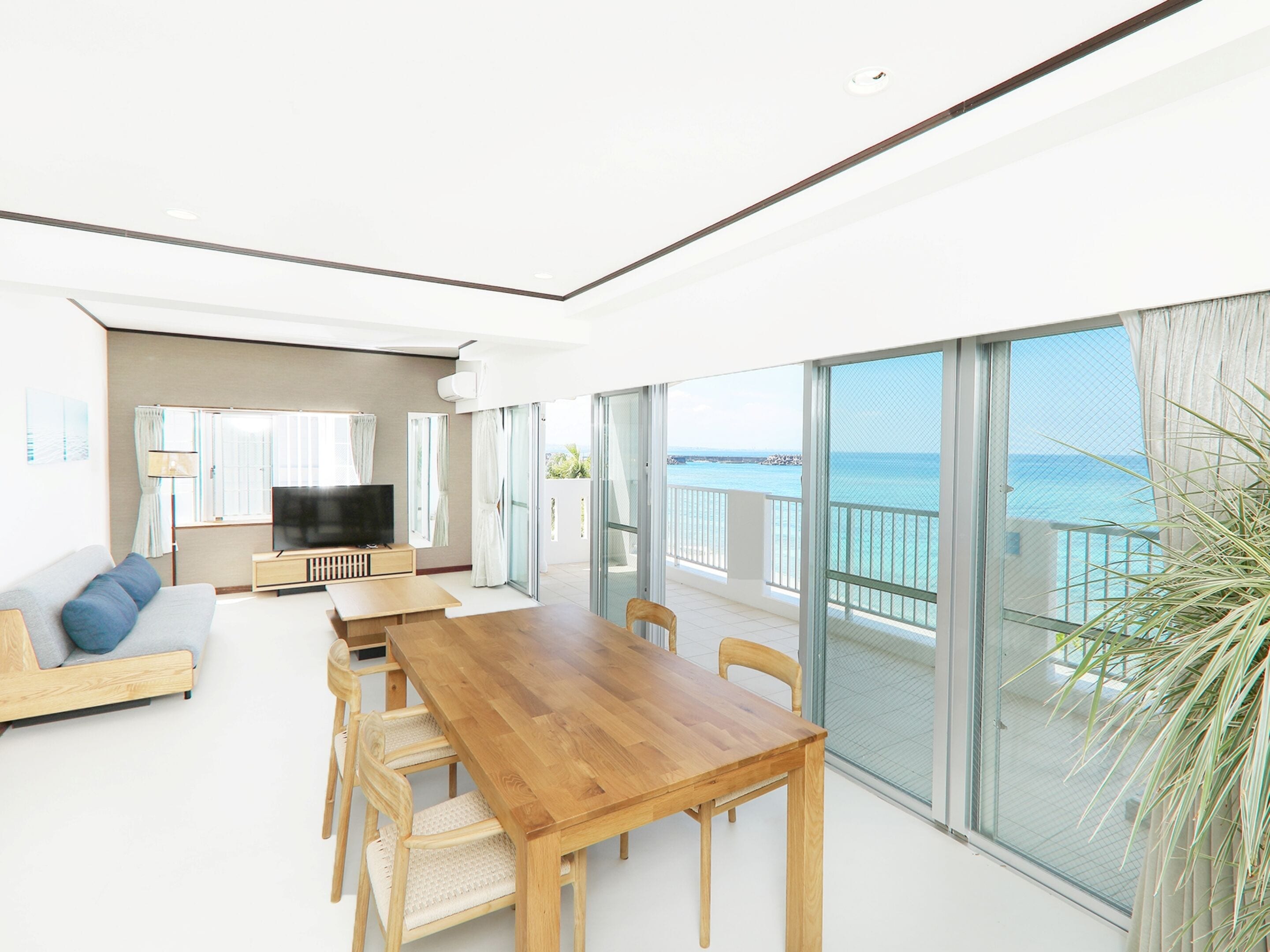 A modern living room with a wooden dining table, sofa, and TV.
