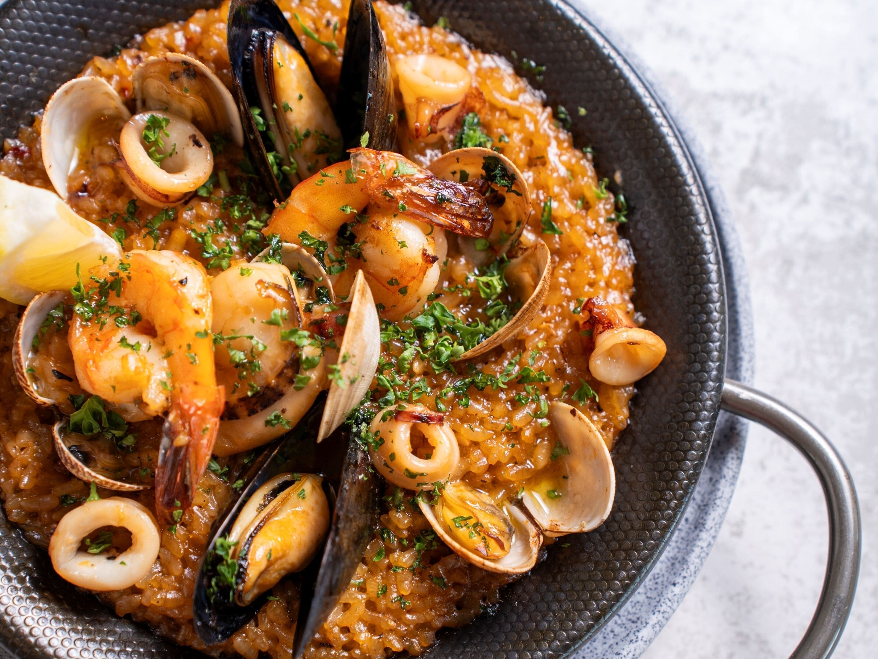 Un plato de mariscos con mejillones, almejas y camarones en una sartén.