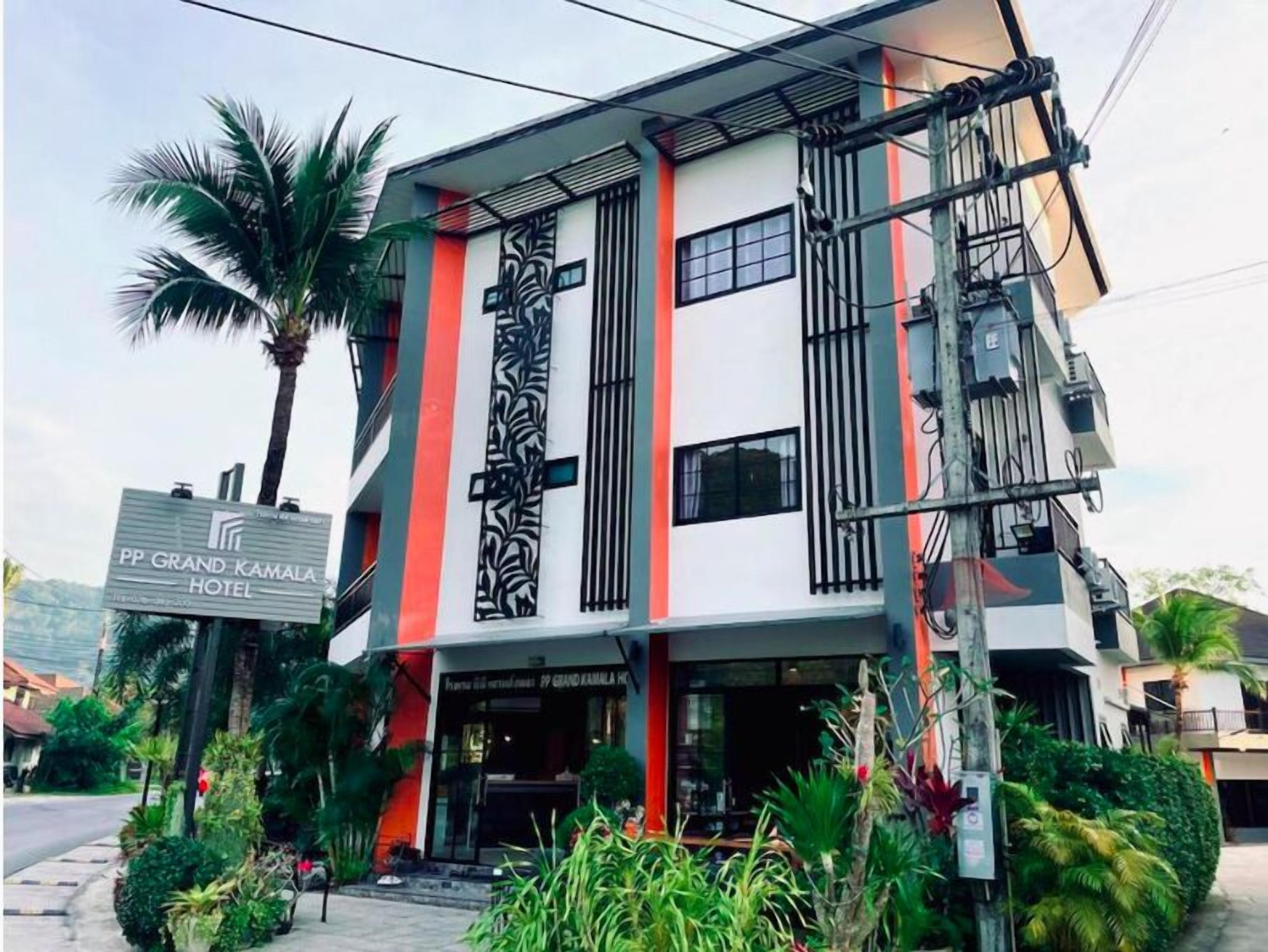 Un hôtel moderne, reconnaissable à son enseigne imposante, doté de nombreux balcons et entouré d’une végétation luxuriante.