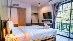 Una habitación de hotel moderna con cama, televisor, balcón con sillas y un armario de madera.