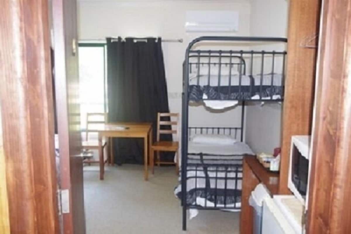 Une chambre de dortoir équipée de lits superposés, d’un bureau, d’une chaise et d’un téléviseur.
