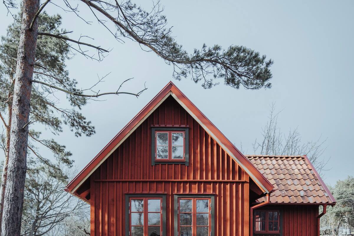 A red wooden house with a gabled roof and two windows on the front.
