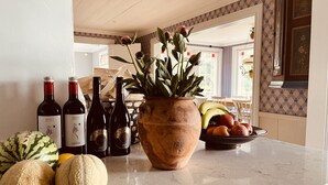 Een aanrecht met wijnflessen, een potplant en een schaal met fruit.