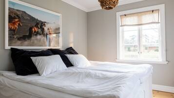 A bedroom with a large bed, a window with a view, and a painting on the wall.