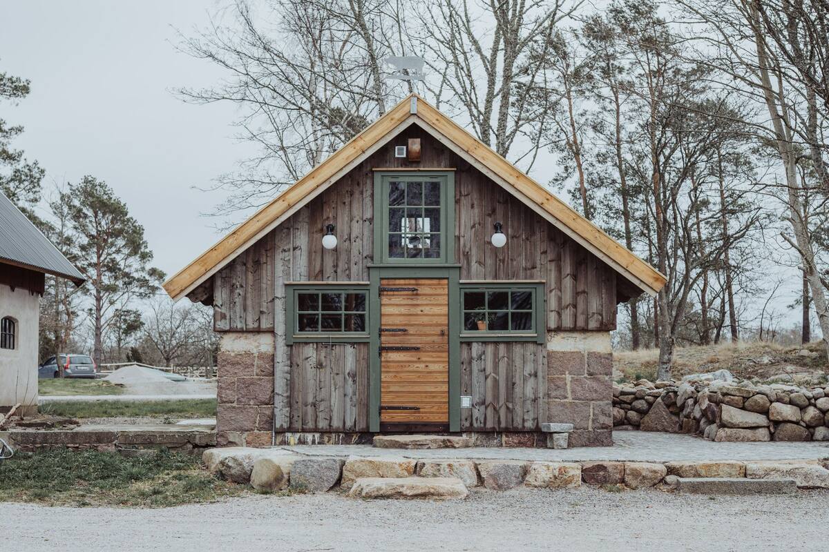 A rustic cabin with a wooden exterior, a gabled roof, and a stone foundation.