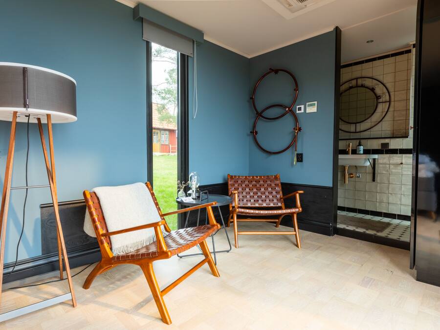 A room with two wooden chairs, a floor lamp, and a large window.