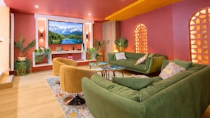 A modern living room with a green sofa, a yellow armchair, and a TV mounted on the wall.