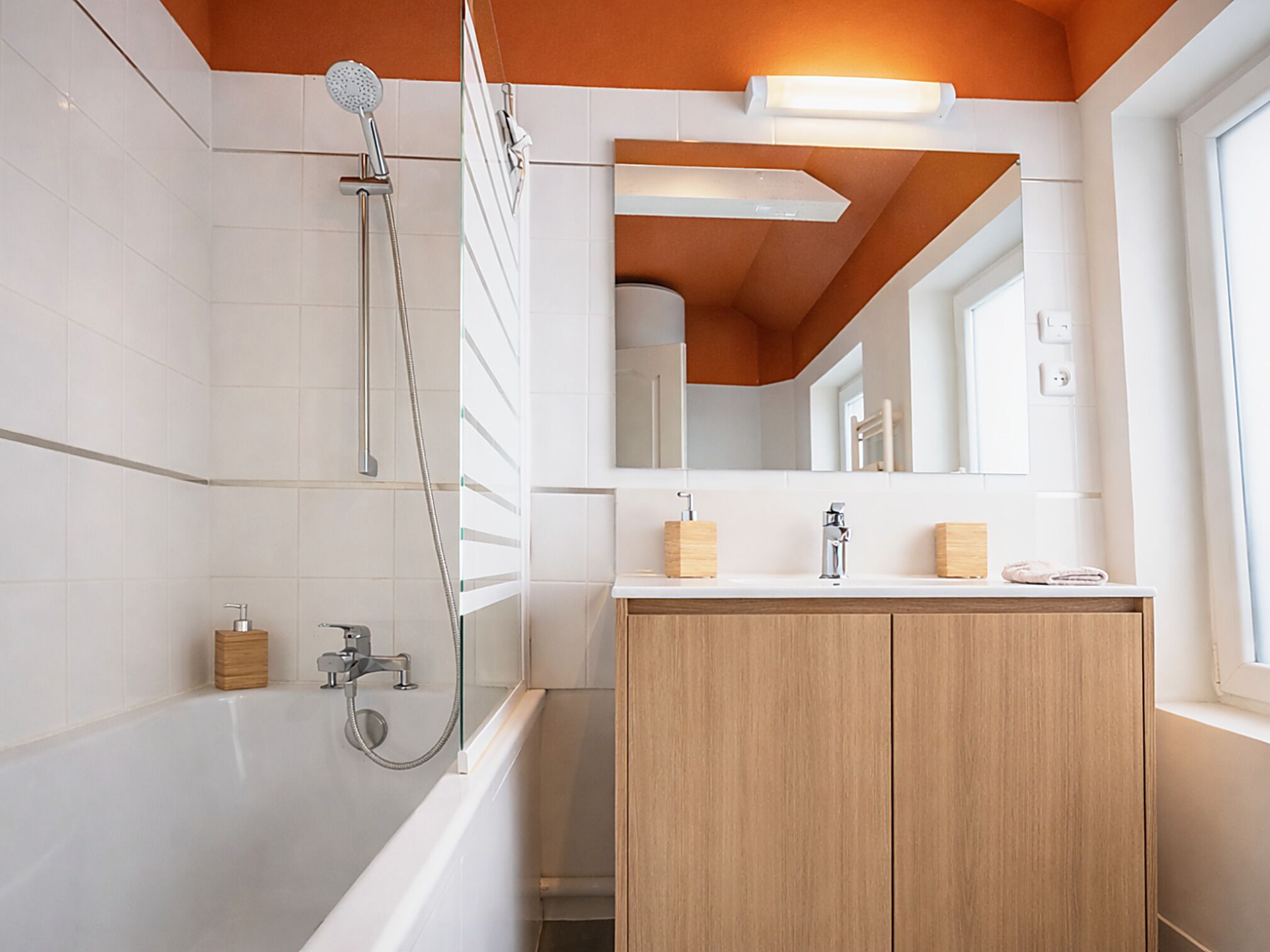 A modern bathroom with a shower, a vanity with a mirror, and a window.