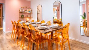 A dining area with a wooden table set for six, surrounded by transparent chairs.