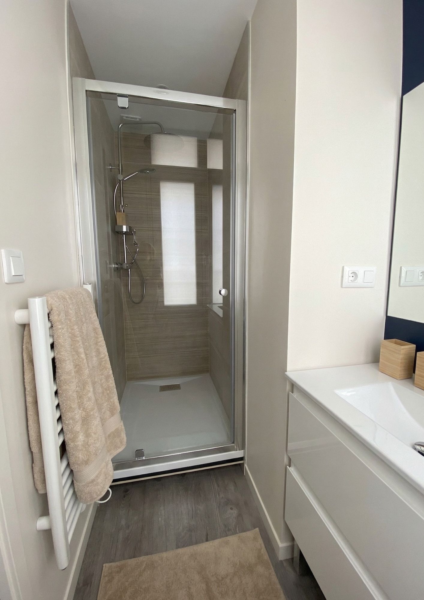 Une salle de bain moderne avec une douche à parois de verre, un lavabo blanc et un miroir.