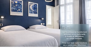 A hotel room with two beds, a large window, and artwork on the wall.