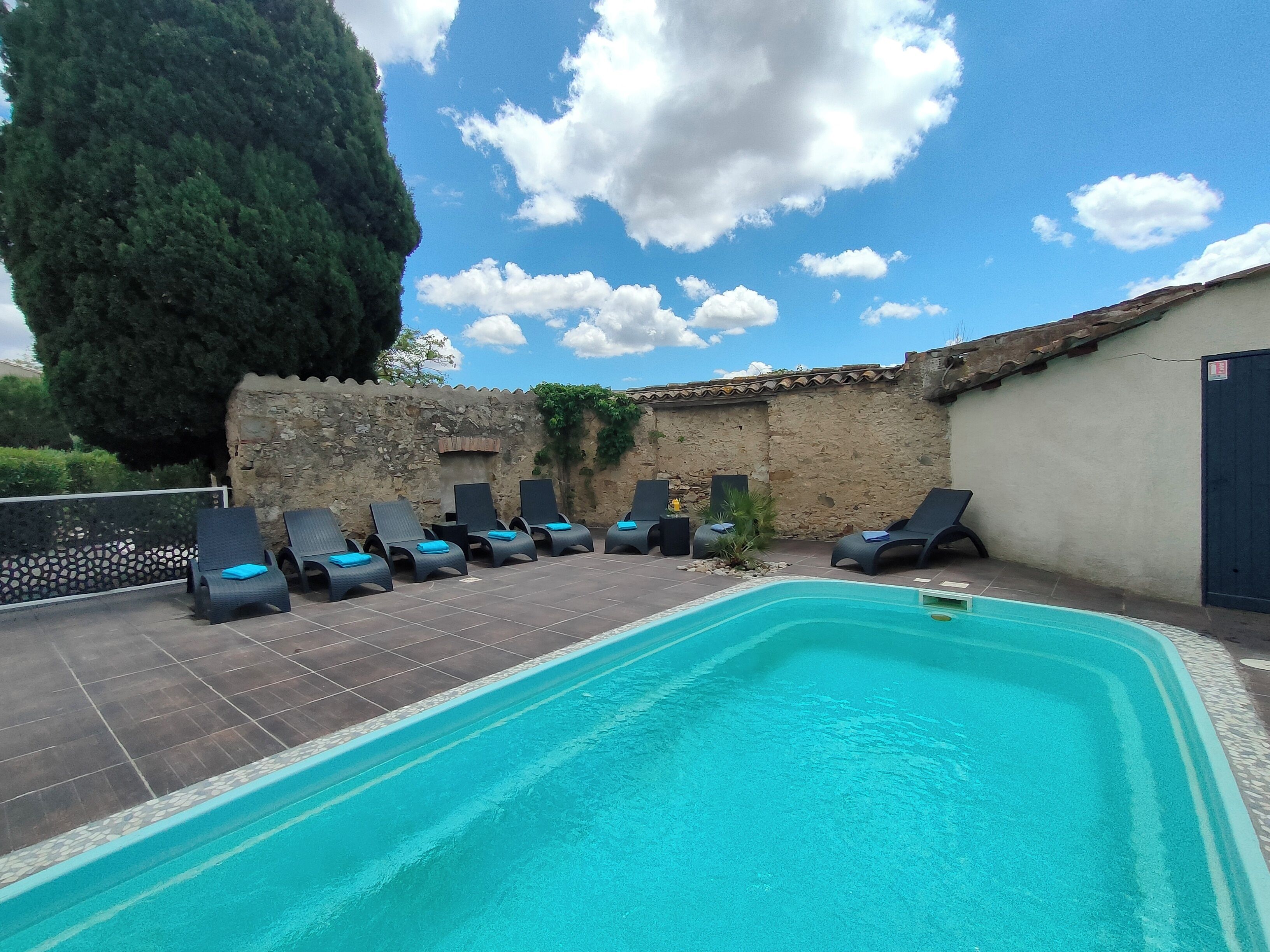 A swimming pool with lounge chairs and a stone wall.