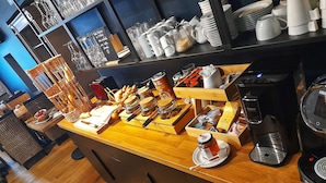 Un bufé de desayuno con diversos alimentos, salsas y máquinas de café.