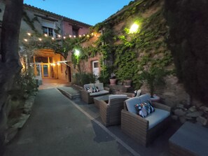 Een terras met wicker meubels en potplanten.