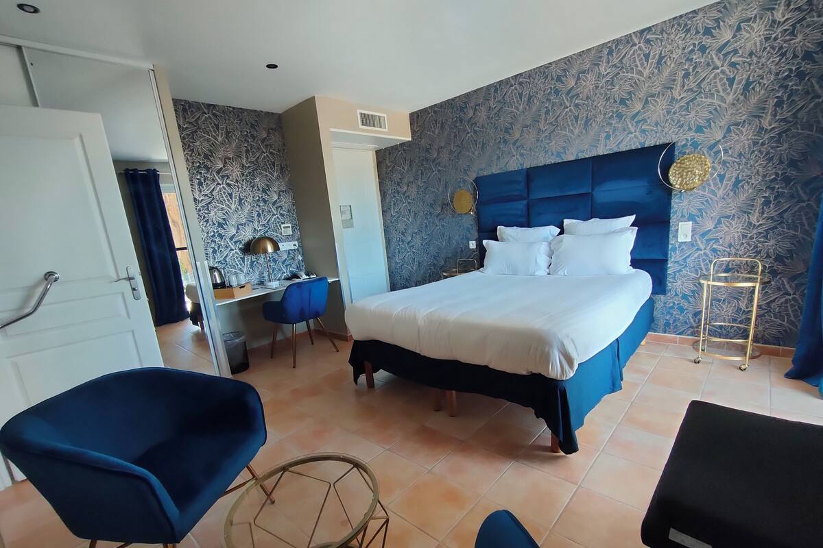 Una habitació d'hotel amb un llit gran, un escriptori, una cadira i una taula petita.