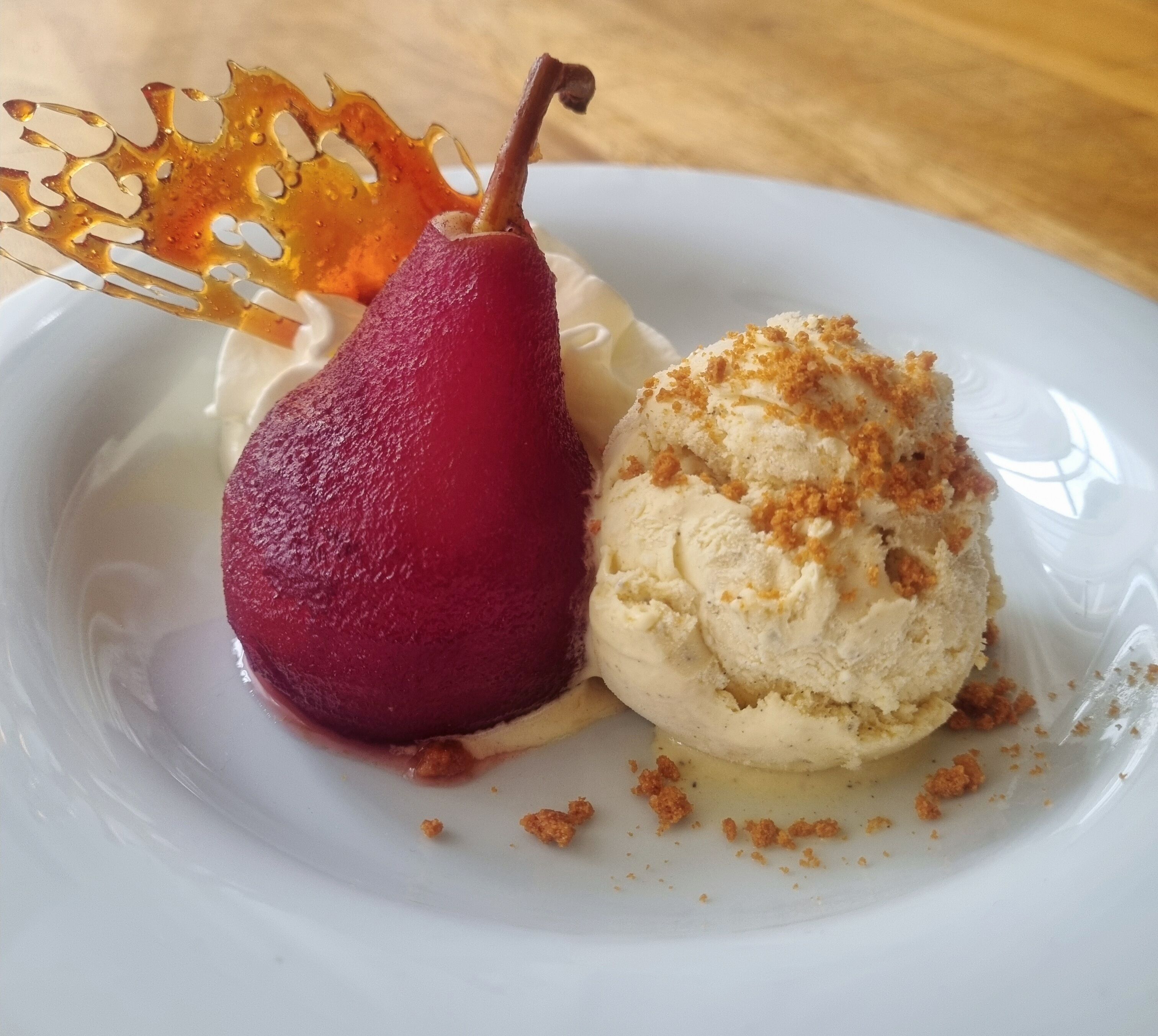 Une assiette à dessert avec une poire et une boule de glace.